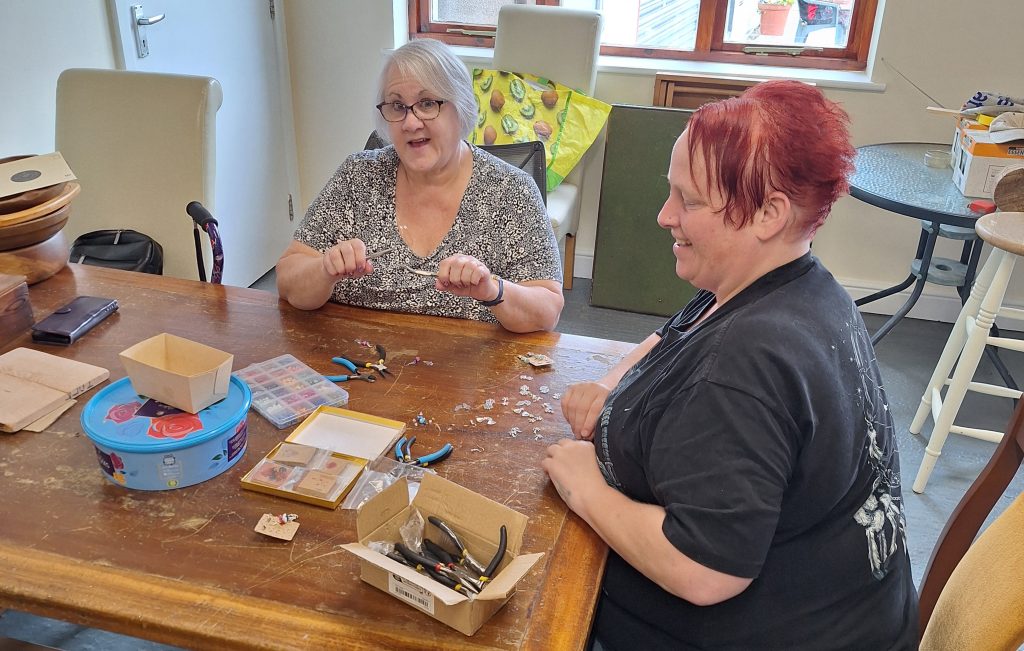 Photo of two ladies working at a table, making crafts.